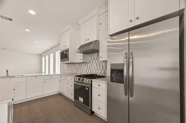 a kitchen with stainless steel appliances granite countertop white cabinets and a refrigerator