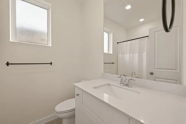 a bathroom with a granite countertop sink a toilet and a mirror