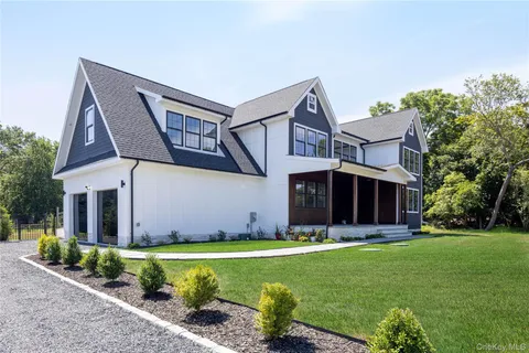 a view of a house with a yard potted plants and a large tree