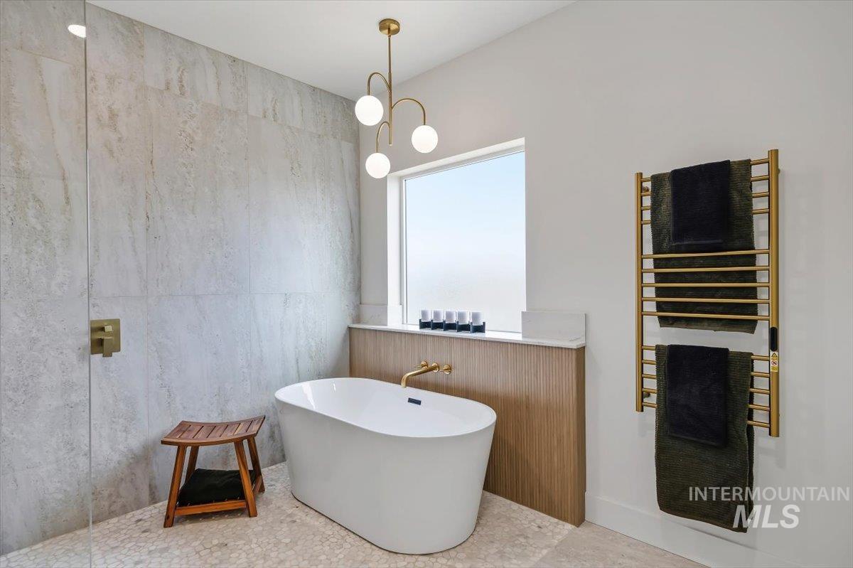 2005 Sparrow Street Rupert, ID 83350 - Photo 18 of 30 Freestanding soaking tub with brushed gold fixtures, surrounded by large format tile walls and pebble flooring