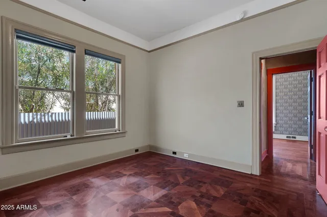 an empty room with wooden floor fan and windows