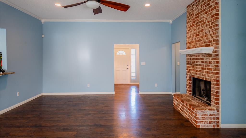 124 Topaz Circle Hewitt, TX 76643 - Photo 6 of 28 Unfurnished living room featuring dark wood finished floors, ornamental molding, a ceiling fan, a fireplace, and recessed lighting
