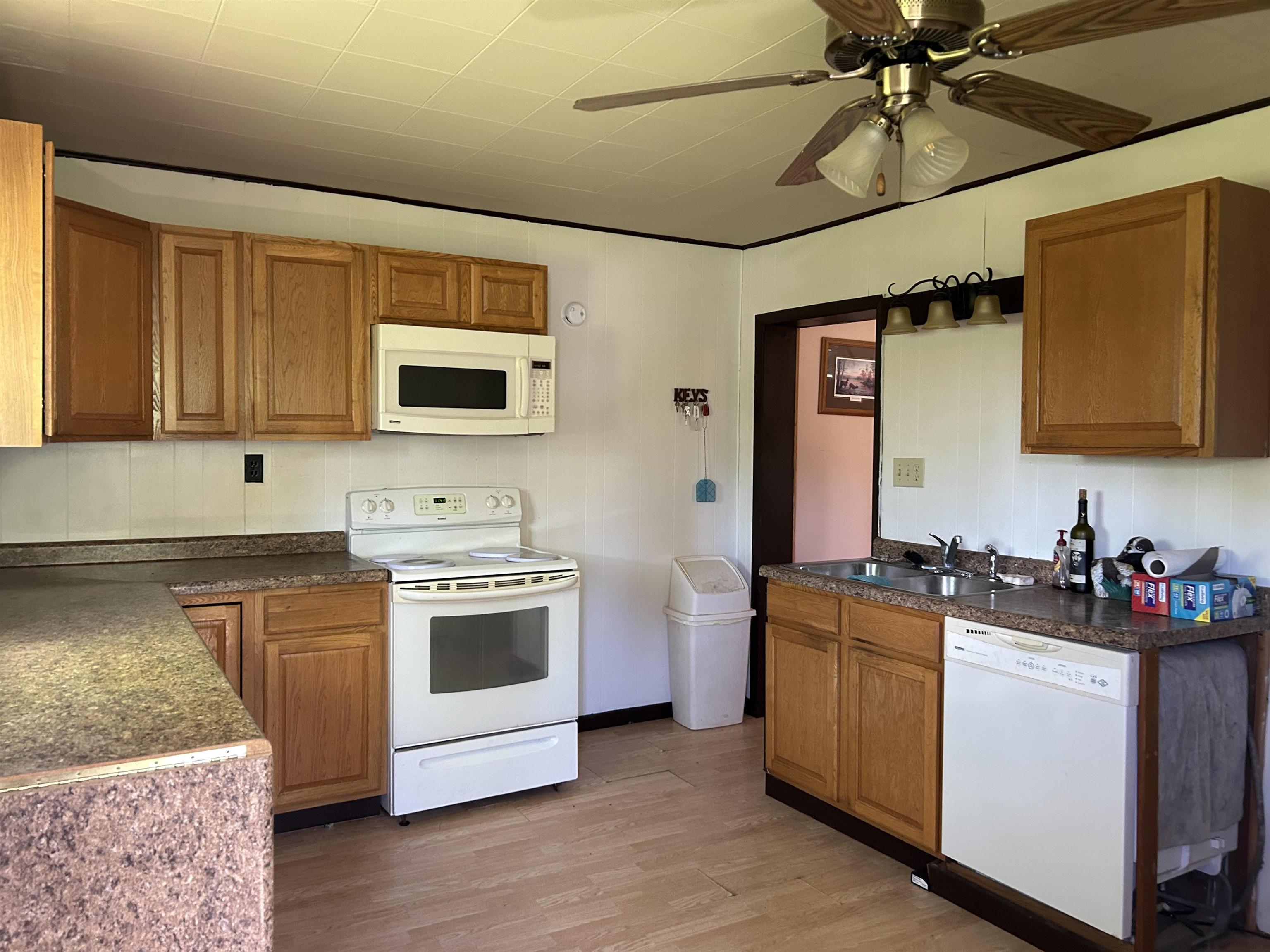 157 East 2nd Street Glidden, WI 54527 - Photo 7 of 15 Kitchen with wood-type flooring, ceiling fan, sink, and white appliances