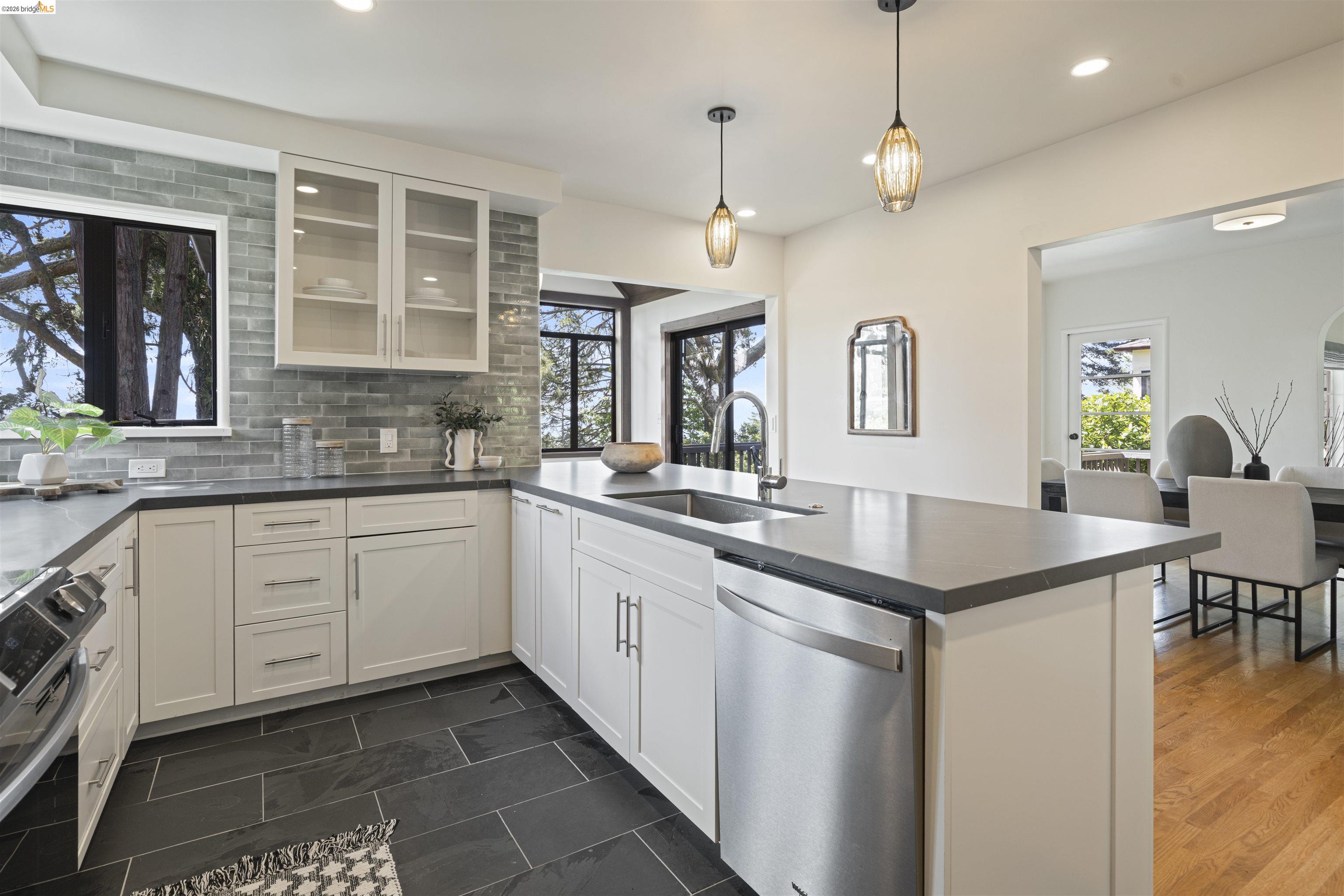 1170 Sterling Avenue Berkeley, CA 94708 - Photo 10 of 52 Kitchen with stainless steel appliances, tasteful backsplash, a peninsula, dark countertops, and glass fronted cabinets