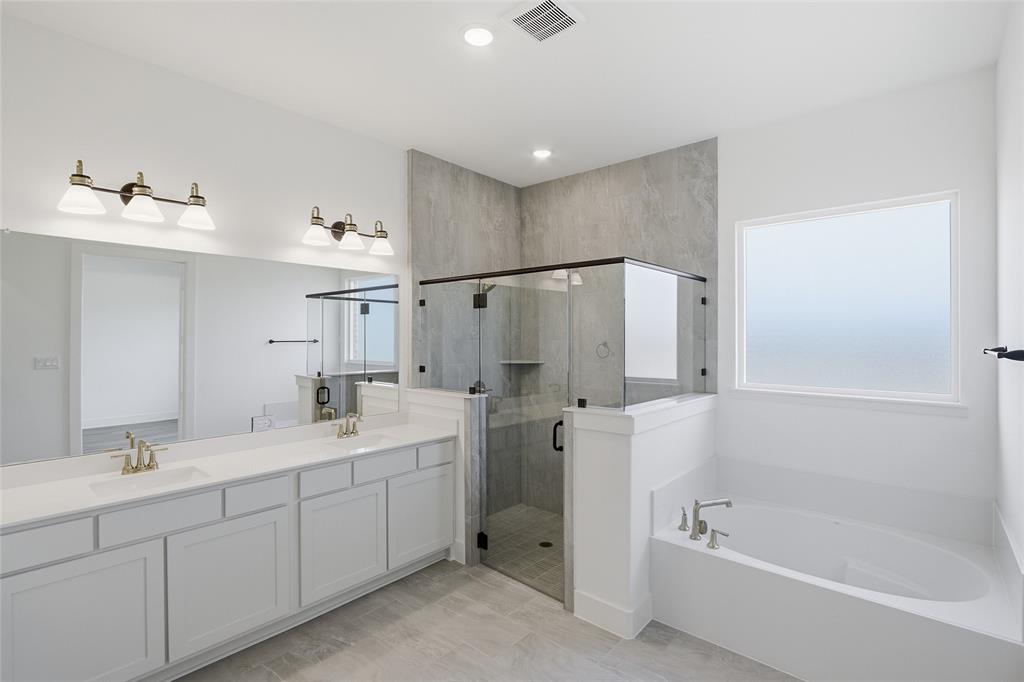 1005 Webb Court Van Alstyne, TX 75495 - Photo 19 of 38 a spacious bathroom with a double sink mirror and a bathtub