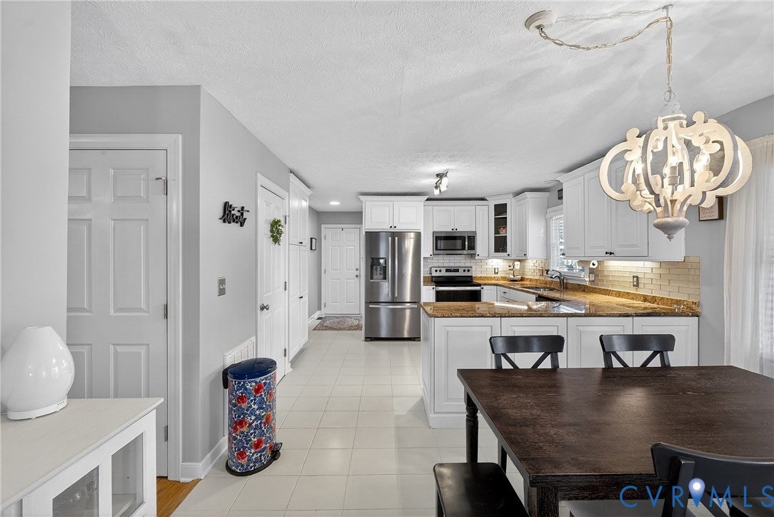 7443 Pinehurst Drive Quinton, VA 23141 - Photo 17 of 49 a kitchen with a dining table chairs refrigerator and cabinets