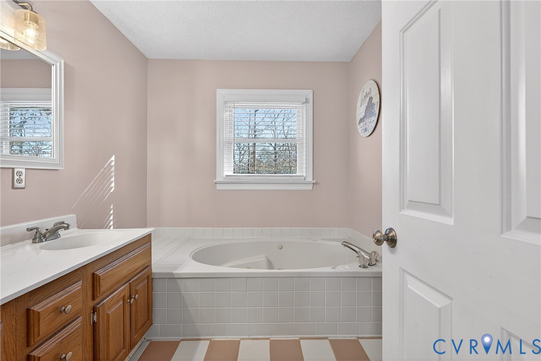 7443 Pinehurst Drive Quinton, VA 23141 - Photo 38 of 49 a bathroom with a granite countertop tub sink and mirror