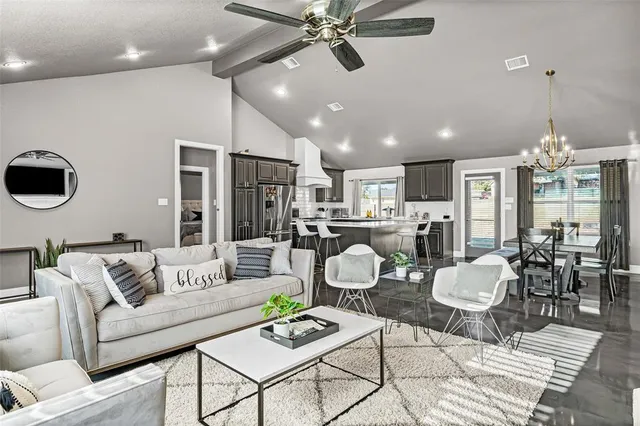 a living room with furniture kitchen view and a chandelier