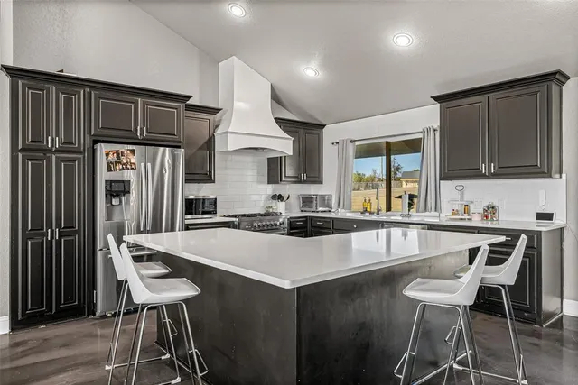 a kitchen with granite countertop a stove a sink cabinets and a refrigerator