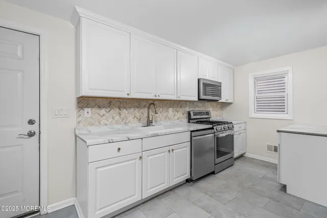 a kitchen with granite countertop white cabinets and stainless steel appliances