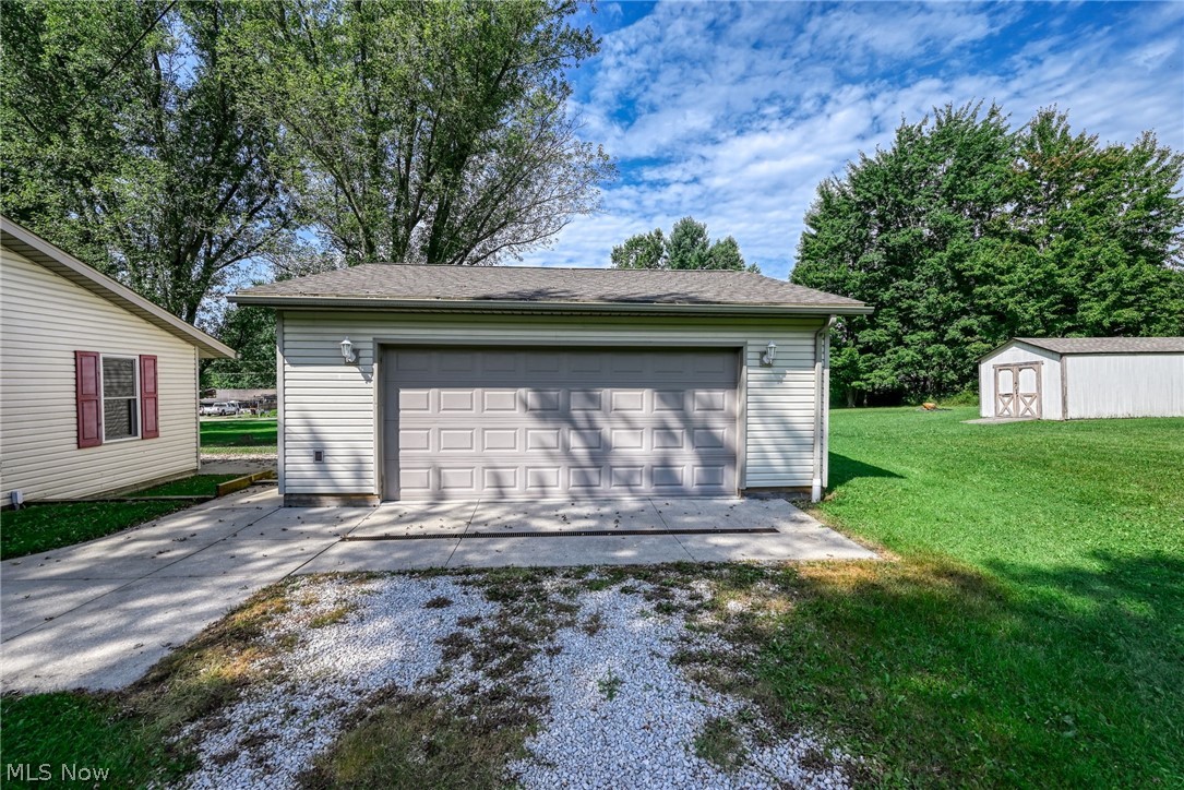 6503 Garrett Road Ravenna, OH 44266 - Photo 21 of 50 Detached garage with panel door, concrete driveway, additional storage shed, and expansive lawn