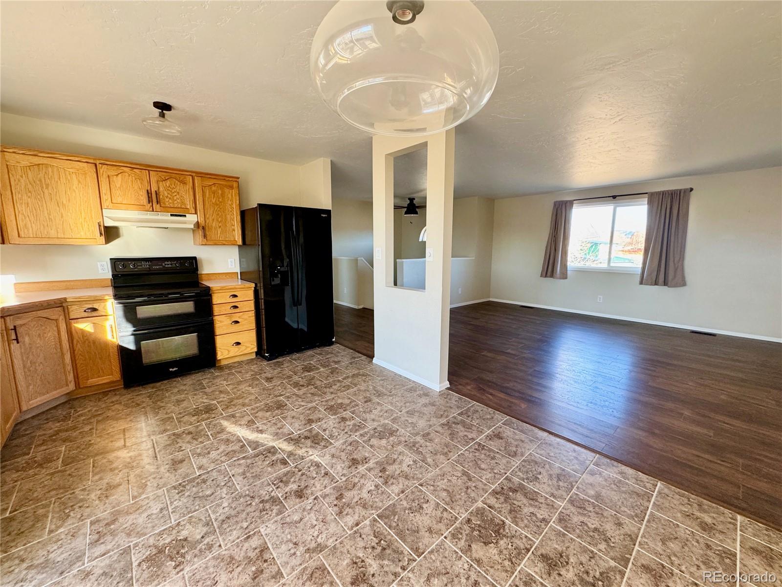 401 Rider Road Rangely, CO 81648 - Photo 13 of 23 a kitchen with granite countertop a refrigerator and a stove top oven