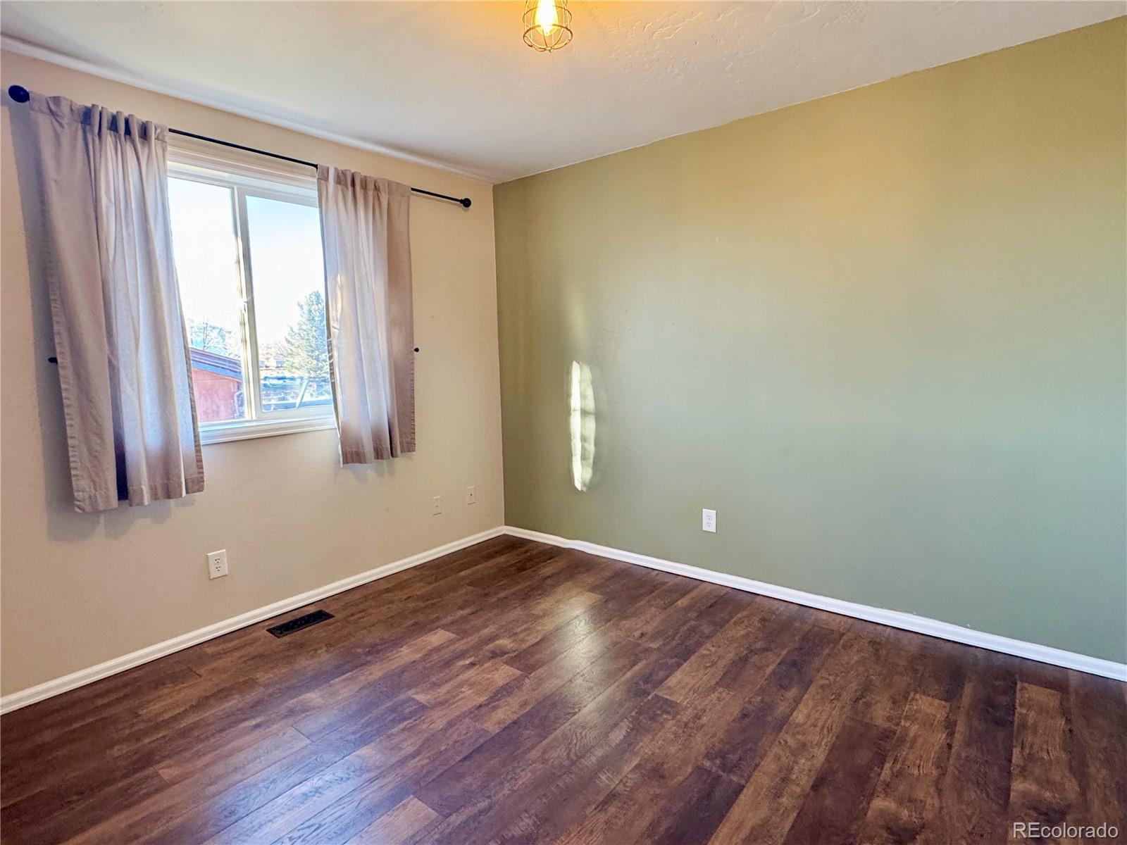 401 Rider Road Rangely, CO 81648 - Photo 14 of 23 a view of an empty room with wooden floor and a window