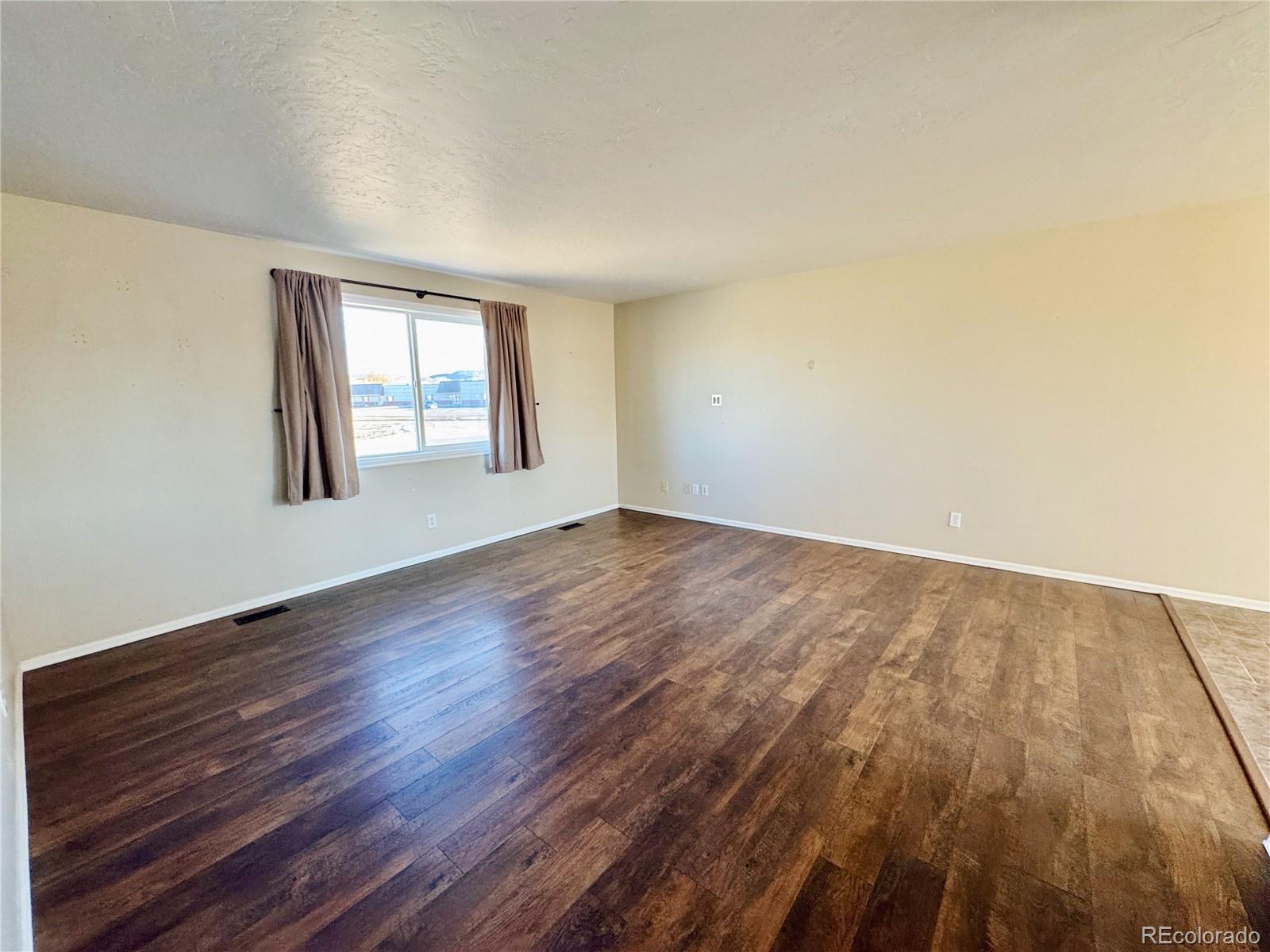 401 Rider Road Rangely, CO 81648 - Photo 9 of 23 a view of an empty room with wooden floor and window