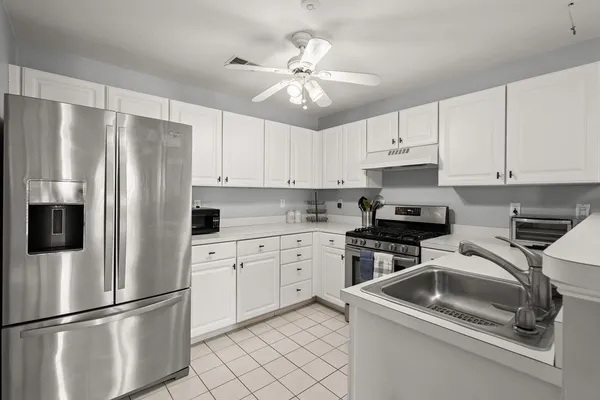 a kitchen with stainless steel appliances granite countertop a refrigerator sink and white cabinets