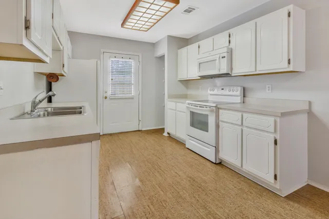 a kitchen with white cabinets and sink