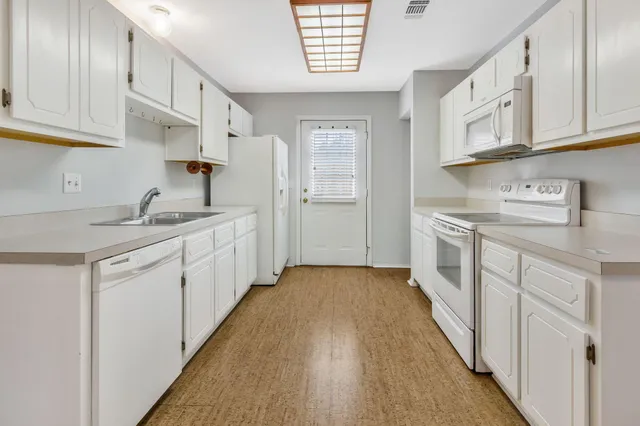 a kitchen with white cabinets and sink