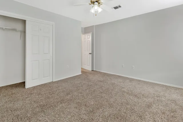 an empty room with windows and chandelier fan