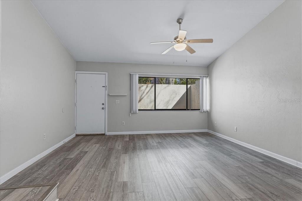 2508 Southwest 35th Place, Unit D19 Gainesville, FL 32608 - Photo 6 of 25 an empty room with wooden floor chandelier and fan