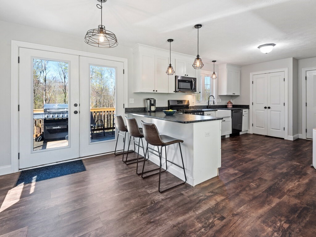 56 Carter Road Westminster, MA 01473 - Photo 8 of 36 a kitchen with stainless steel appliances a stove top oven a sink a refrigerator a dining table and chairs with wooden floor