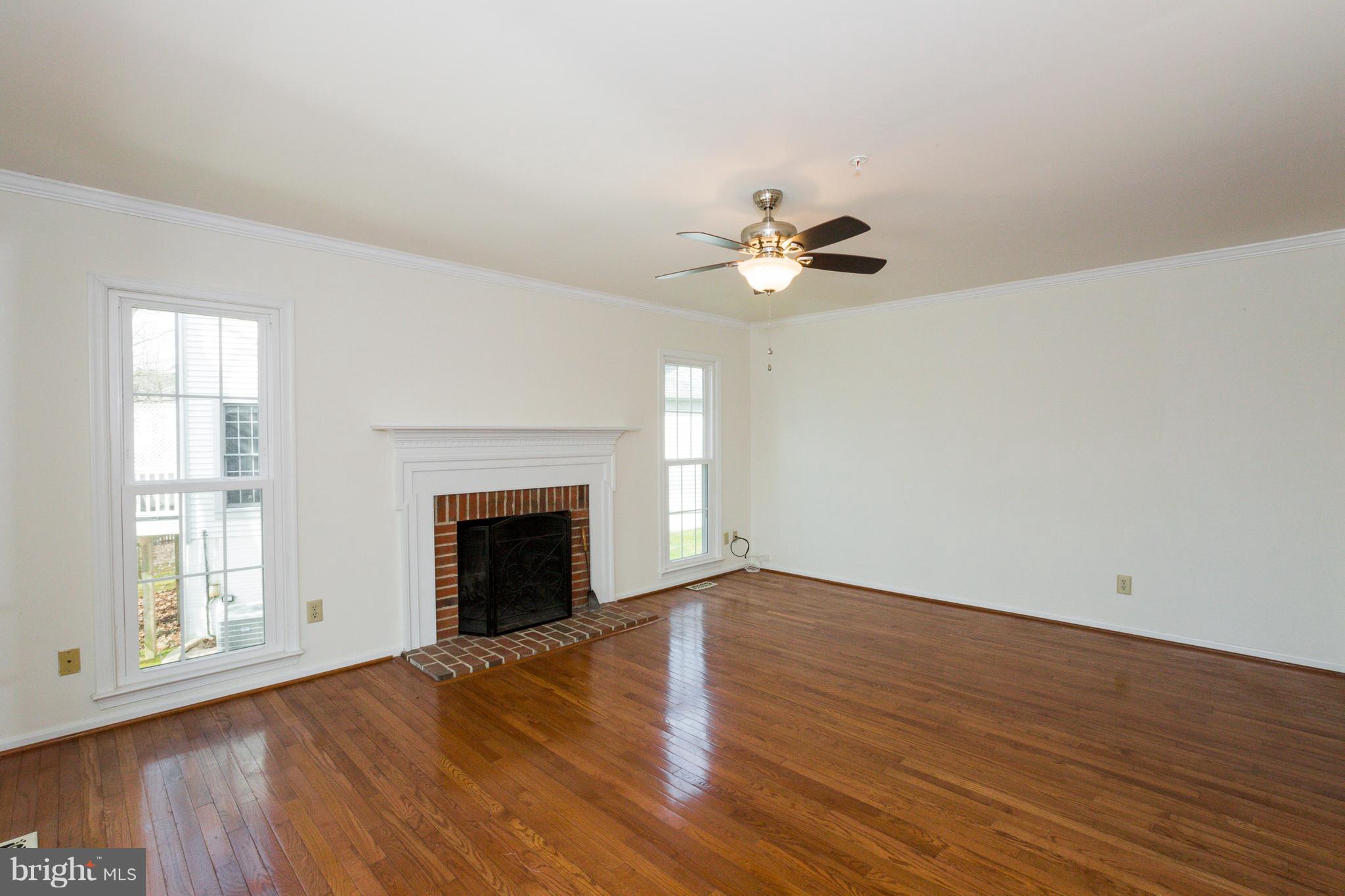 8402 Shadeland Road Laurel, MD 20724 - Photo 10 of 30 an empty room with wooden floor fireplace and fan