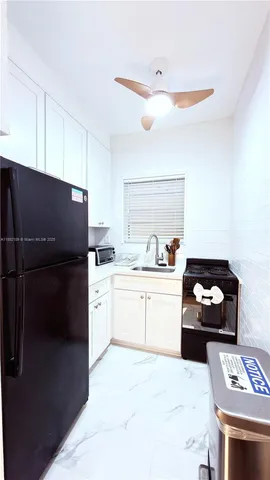 a kitchen with a refrigerator and white cabinets