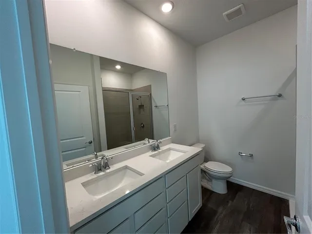 a bathroom with a granite countertop sink toilet and mirror