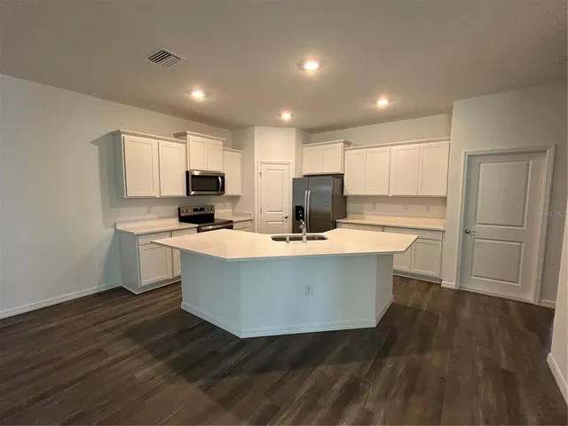 a view of kitchen with stainless steel appliances a stove top oven a refrigerator a sink and a microwave