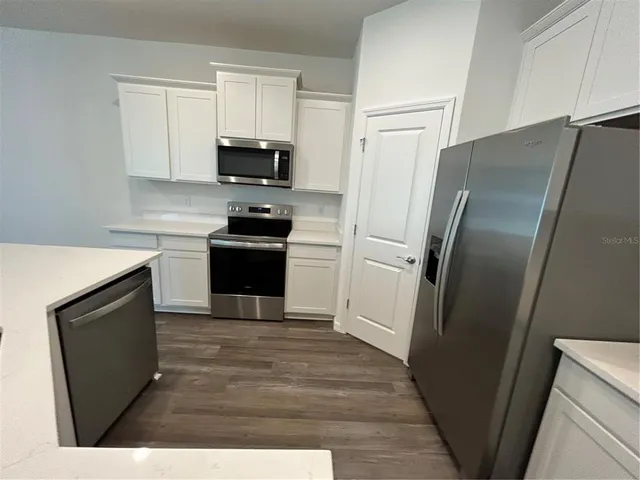 a kitchen with stainless steel appliances a refrigerator a sink a stove a microwave and cabinets