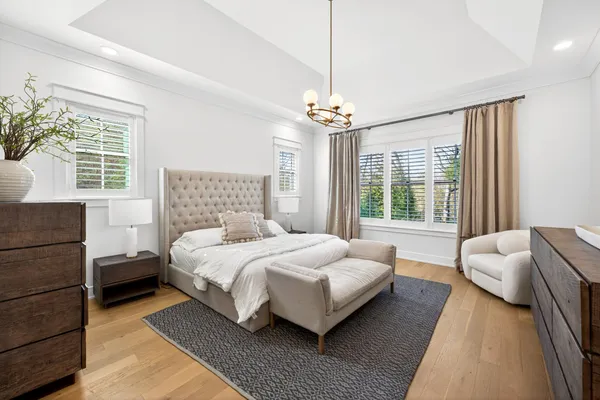 a bedroom with a bed chandelier and windows