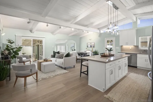 a large white kitchen with living room and white cabinets