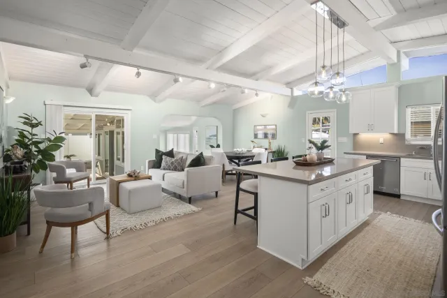 a large white kitchen with living room and white cabinets