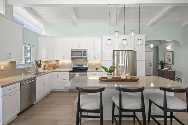 a kitchen with white cabinets and chairs