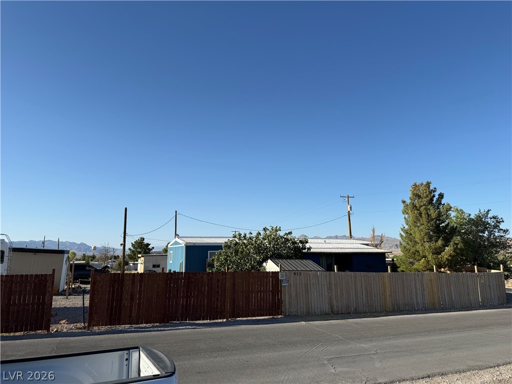 975 Sky Road Indian Springs, NV 89018 - Photo 2 of 4 A well-maintained wooden fence encloses a charming property with mature trees and mountain views.