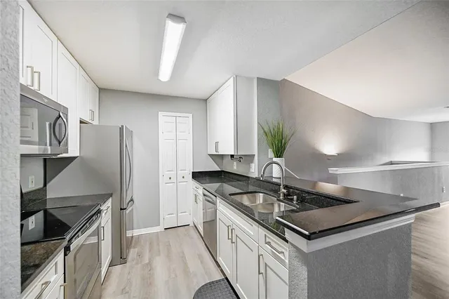 a kitchen with granite countertop a sink stainless steel appliances and cabinets