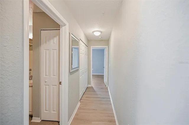 a view of a hallway with wooden floor and closet