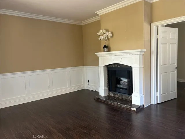 a view of an empty room with wooden floor and a fireplace