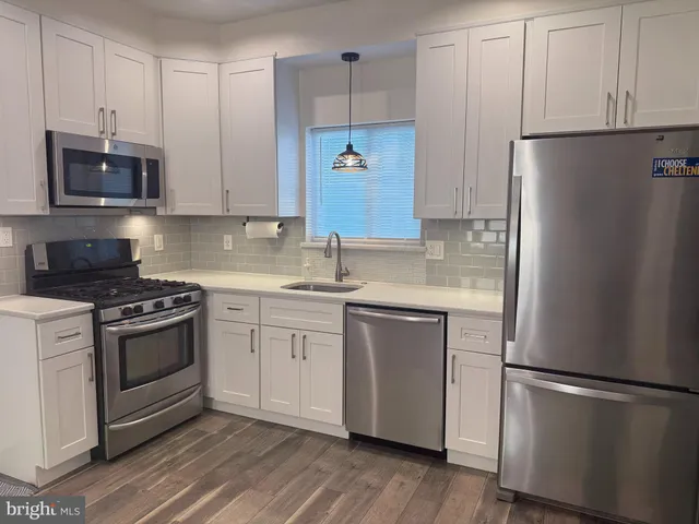 a kitchen with stainless steel appliances granite countertop a refrigerator stove a sink and white cabinets