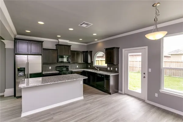 a large kitchen with stainless steel appliances granite countertop a large counter top a stove a sink and a refrigerator