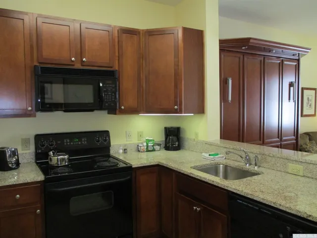 a kitchen with granite countertop wood cabinets stainless steel appliances and a sink