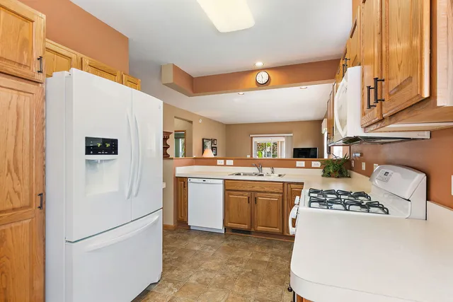 a kitchen with stainless steel appliances granite countertop a refrigerator a stove and a sink with wooden floor