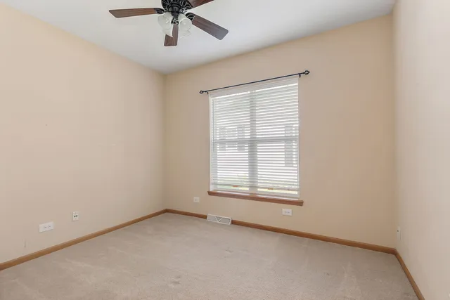 an empty room with a window and a ceiling fan