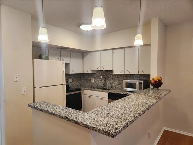 a kitchen with stainless steel appliances granite countertop a sink refrigerator and microwave