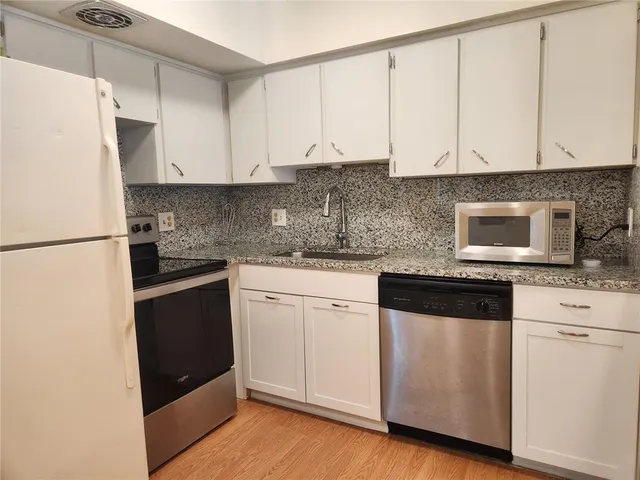 a kitchen with granite countertop white cabinets and white appliances