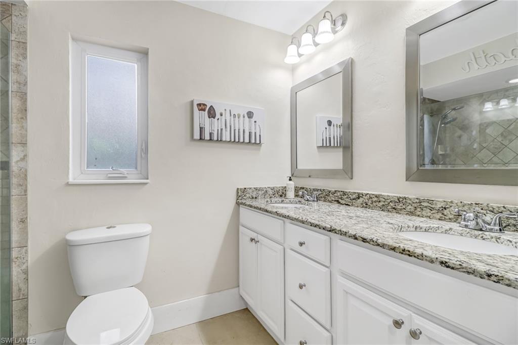 148 Pebble Beach Boulevard Naples, FL 34113 - Photo 11 of 24 a bathroom with a granite countertop toilet sink and mirror