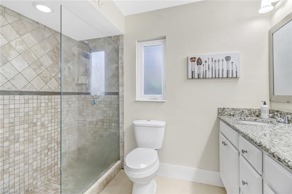 148 Pebble Beach Boulevard Naples, FL 34113 - Photo 12 of 24 a bathroom with a granite countertop toilet a sink and a shower