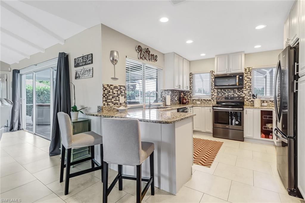 148 Pebble Beach Boulevard Naples, FL 34113 - Photo 7 of 24 a kitchen with kitchen island granite countertop wooden cabinets and stainless steel appliances