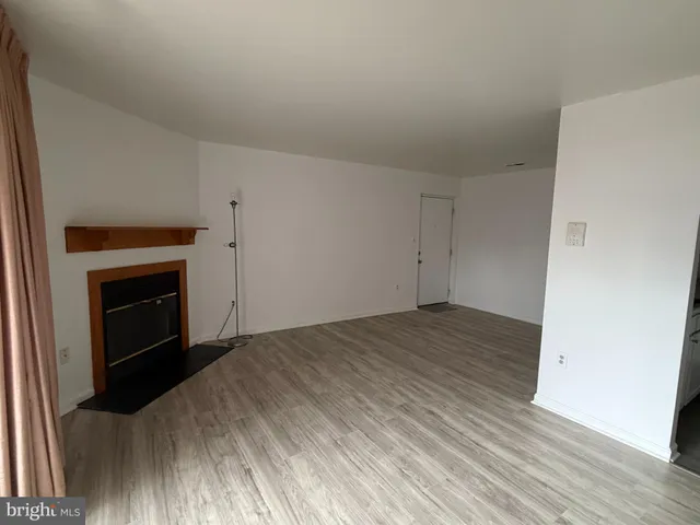 a view of empty room with wooden floor and fireplace