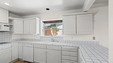 a kitchen with white cabinets and window
