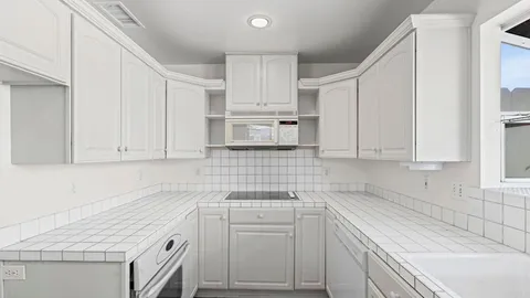 a kitchen with white cabinets and white appliances